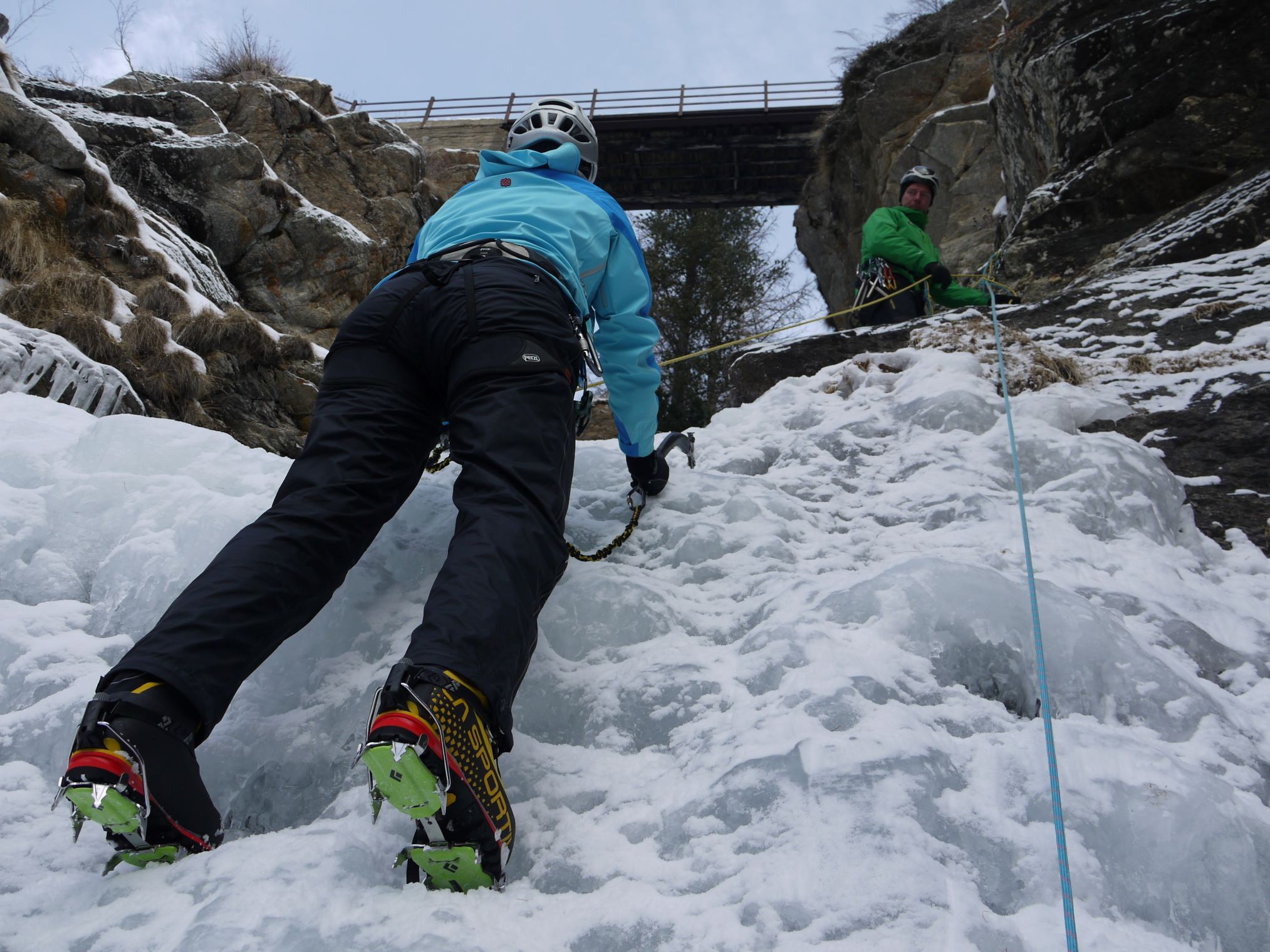 Ice climber belayed from above by guide