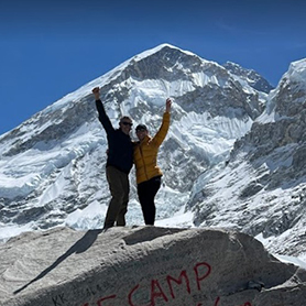 Janice Nicol and her dad stand atop the Everest Base Camp rock, celebrating their achievement.