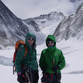 Two climbers stand in the Western Cwm, looking up towards the impending Lhotse Face and towering peak of Mount Lhotse.