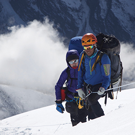 A personal sherpa assists a climber on fixed lines.