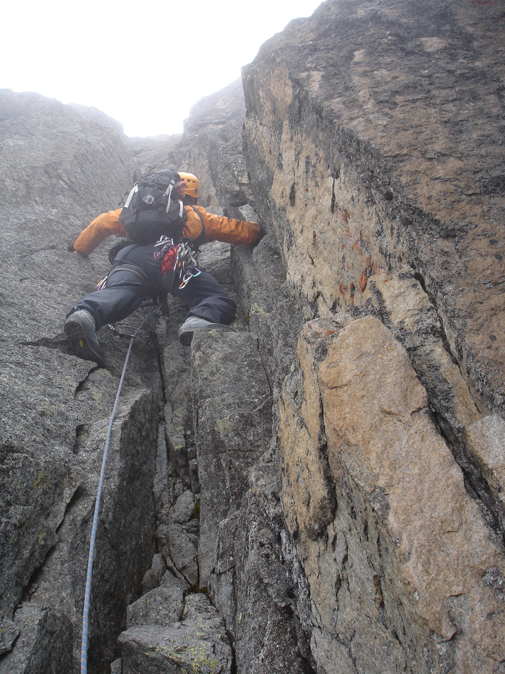 A climber ascends up the rocky technical terrain on Mount Kenya into the clouds.