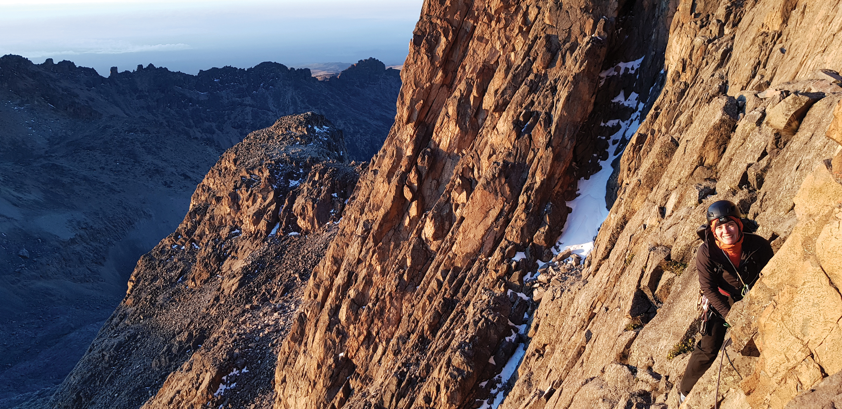 A climber smiles as the sun hits the rocky slab on the lower reaches of Mount Kenya