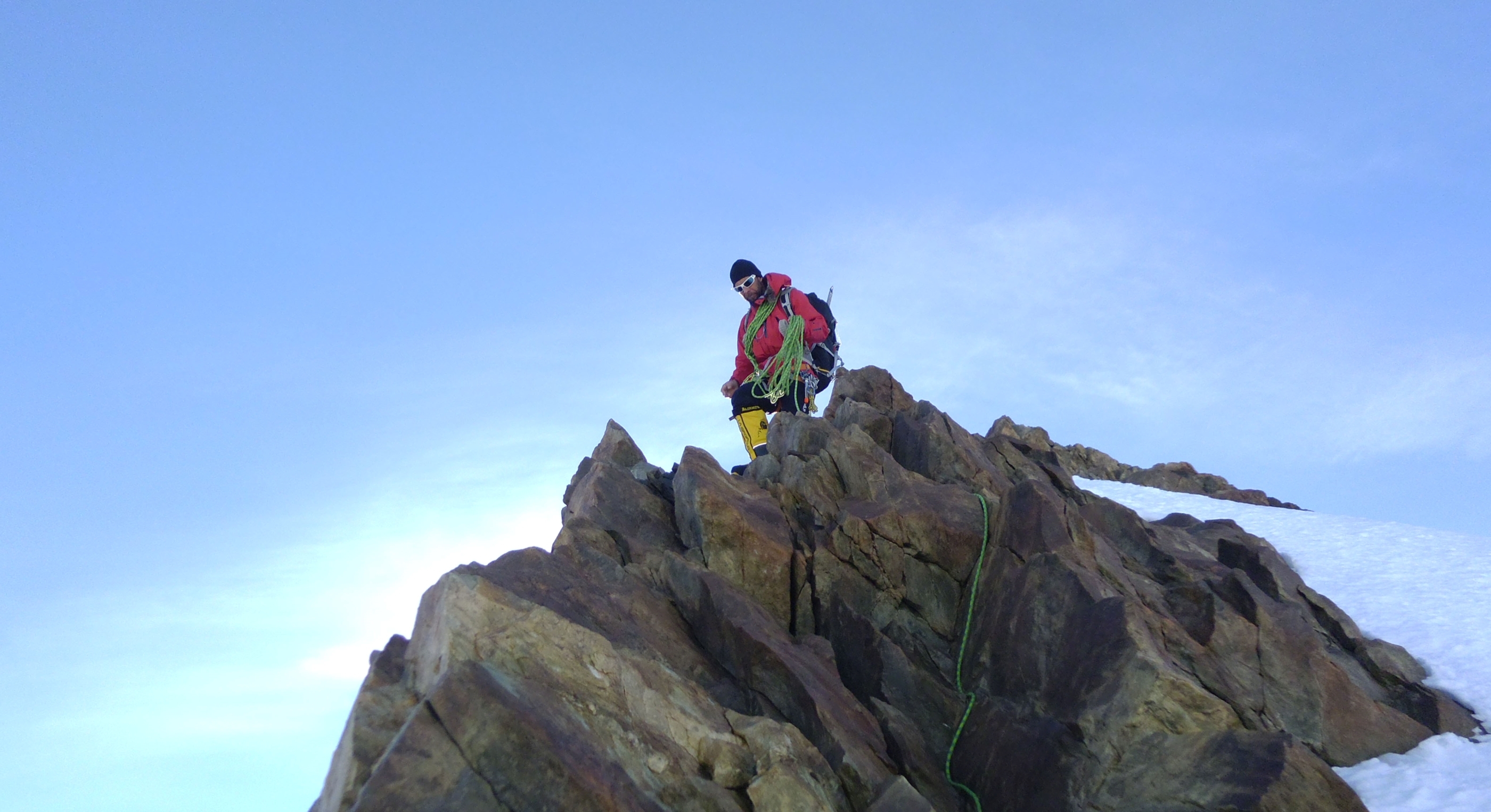 A climber stops at jagged rocks on an Antarctic peak