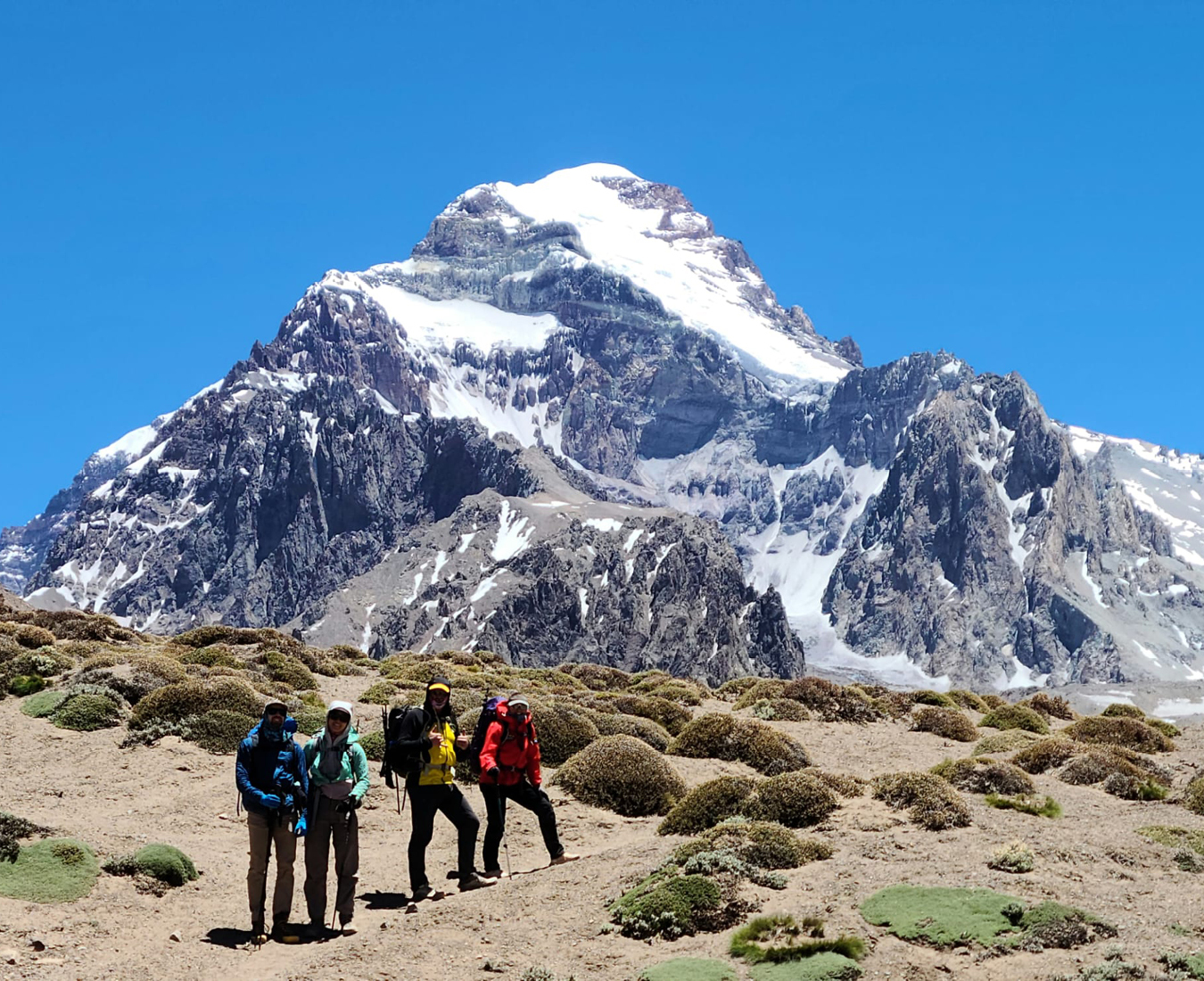 The AC Aconcagua team #1 2025 stand in front of the snow capped peak of Mount Aconcagua, South America's highest peak on their trek into Plaza Argentina Base Camp.