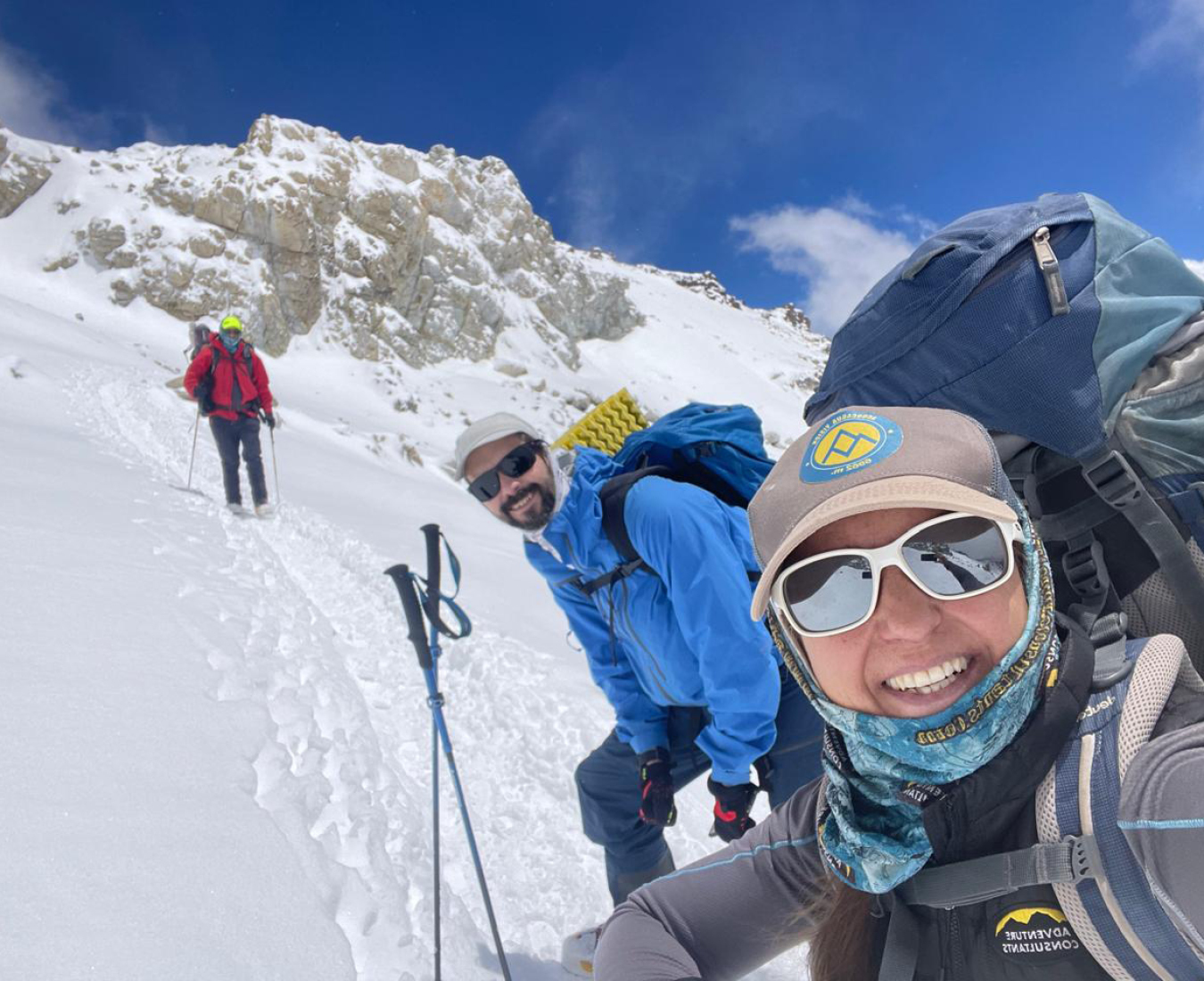 Proof you need to be prepared for snow and ice on Aconcagua as a team makes their way through a trail of snow under blue skies.