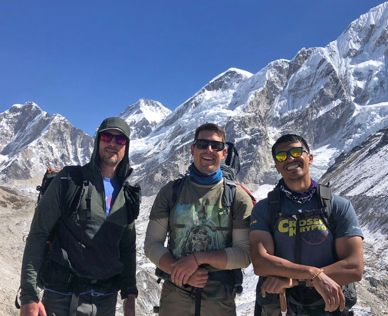 EBC #3 2024 team stand on the edge of the Khumbu Glacier with huge smiles as the reach Everest Base Camp in perfect conditions and fantastic views of Everest and surrounding peaks.