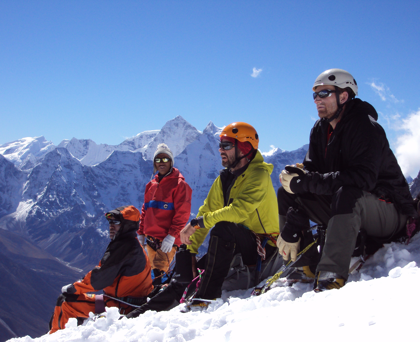 Climbers sit on the summit of Lobuche East taking in the panoramic views across the Himalaya on a perfect blue sky day.