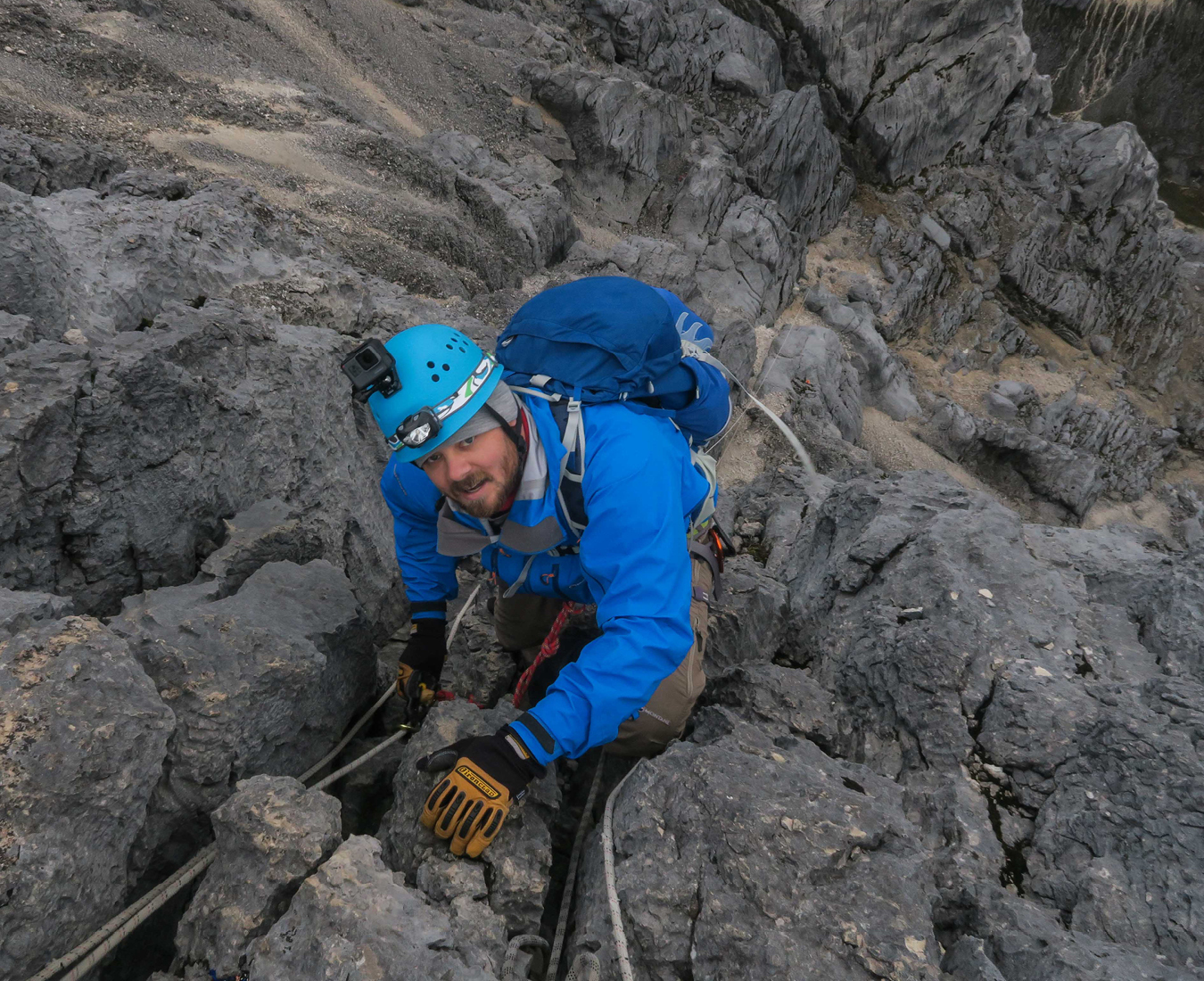 A climber wearing blue looks up as the climb the steep limestone walls on Carstensz Pyramid, Western Papua.