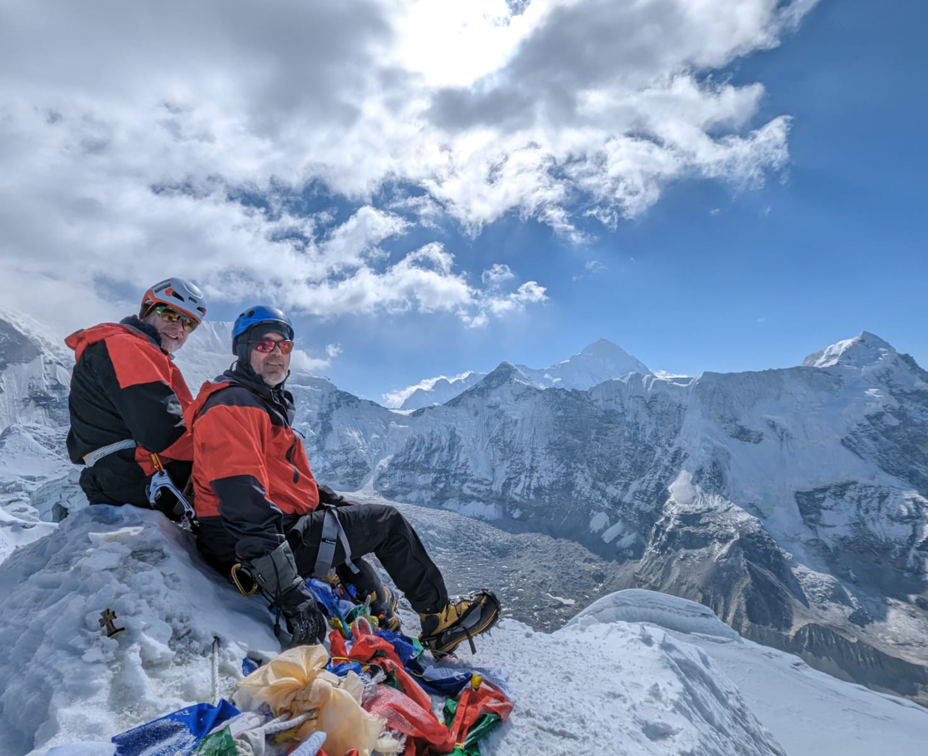 Two climbers, Hugh and John take a rest on the summit of Island Peak, 2023 soaking in views of the surrounding Himalayan giants. Photo by John Lawrence