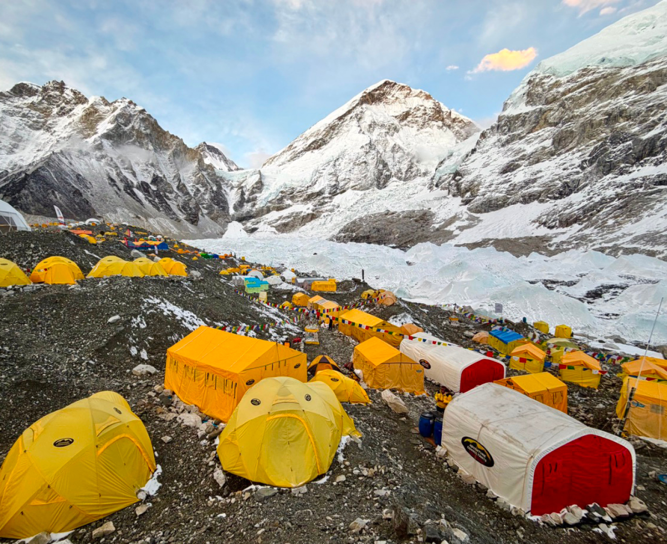 Adventure Consultants Everest Base Camp, brightly coloured tents on the glacial moraine of the Khumbu Glacier. Mount Everest summit in the distance.