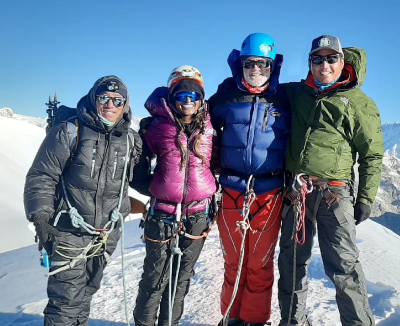 A team of two climbers and their Sherpa guides stand on the summit of Nepal's highest trekking peak, Mera Peak in perfect conditions.