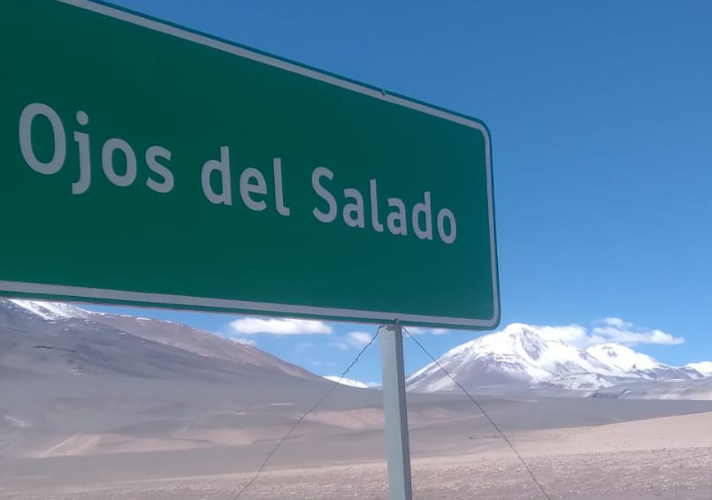 Ojos del Salado road sign and the snow capped world's highest volcano behind.