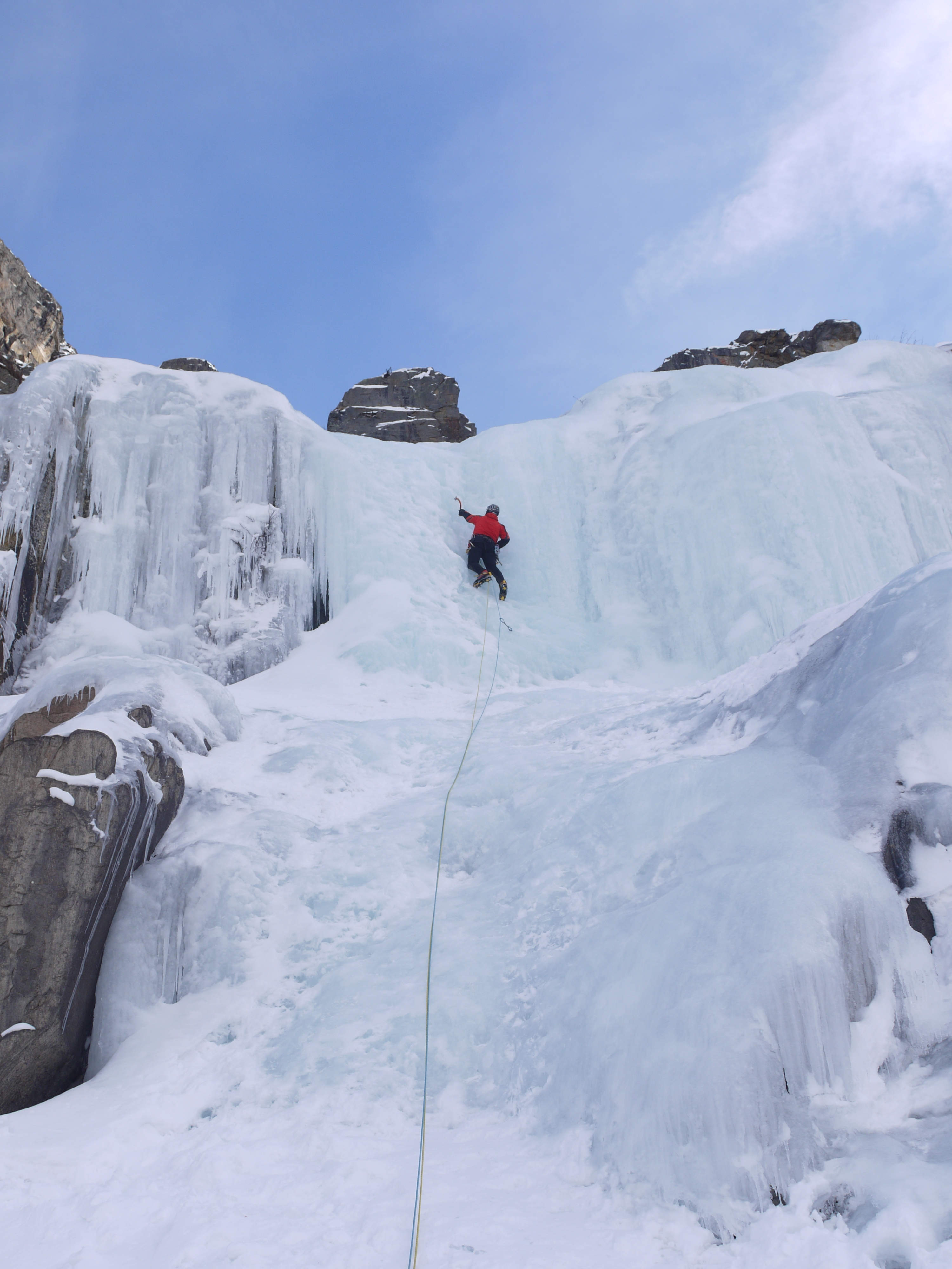 A climber approaches the top of a huge frozen waterfall