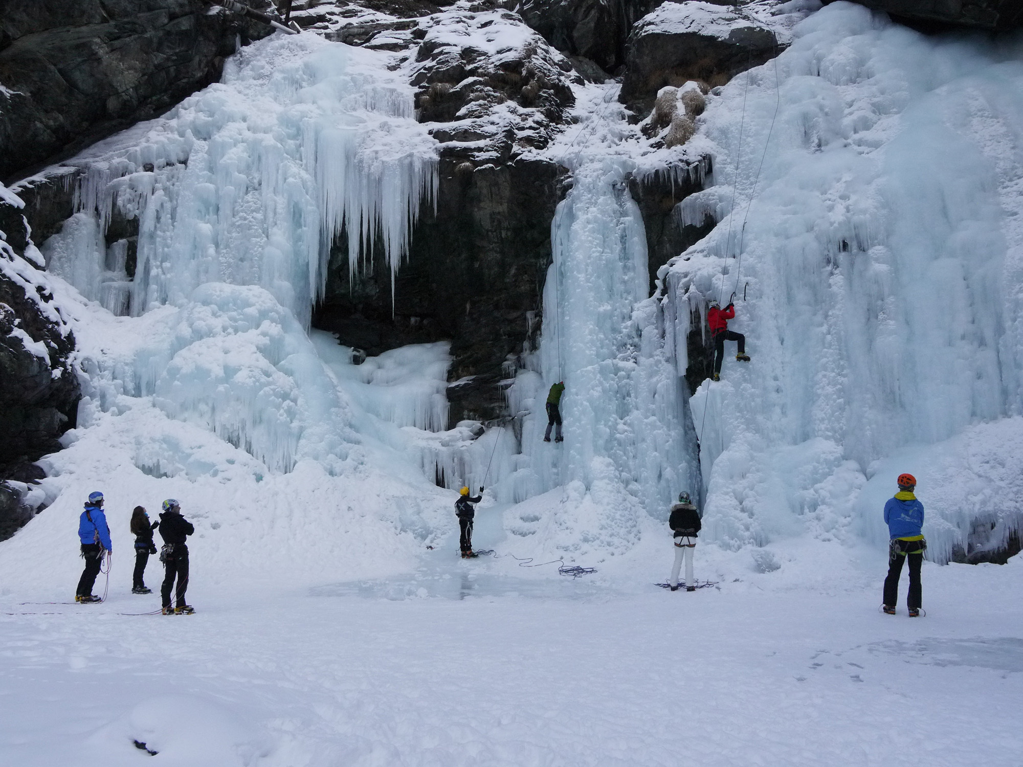 Climbers belay from the base of a frozen waterfall