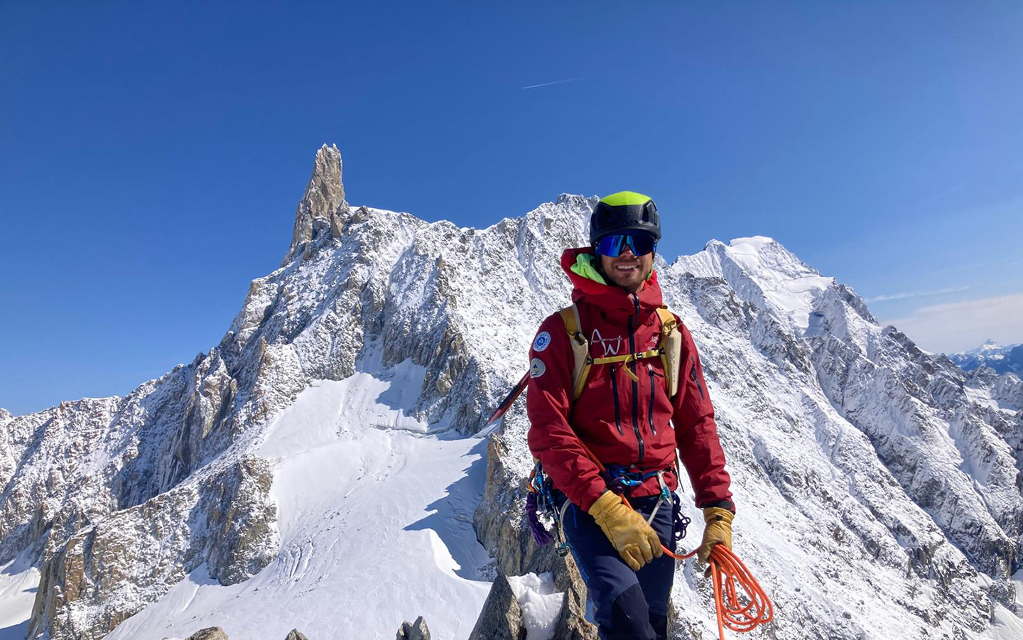 Adventure Consultants IFMGA Mountain & Ski Guide Luigi Zignone high in the European Alps at work, holding a climbing rope in beautiful conditions surrounded by mountains.