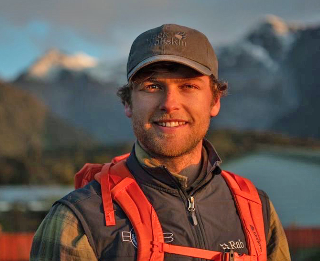 Ryan Colley, Adventure Consultants NZMGA Mountain and Ski guide stands in the evening light with mountains in the background.