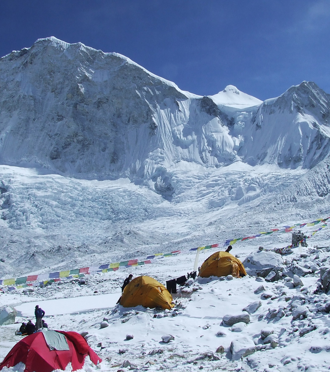 The imposing wall of Baruntse from Base Camp, fresh snow dusting the ground and clear blue sky above.