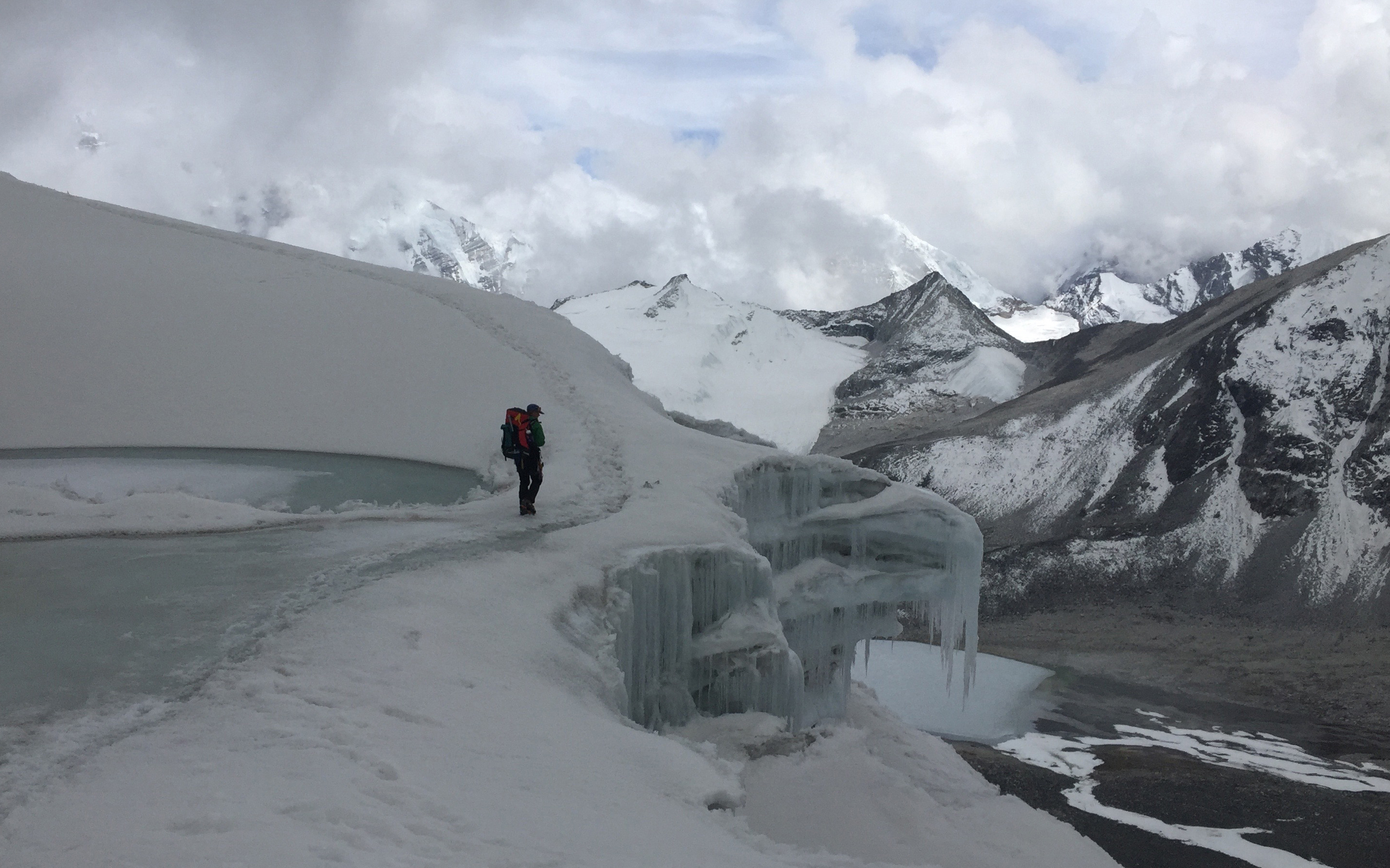 A climber approaches the Amphu Lapcha pass from the Honku Baruntse side, the Imja (Island Peak) valley visible in the distance below.