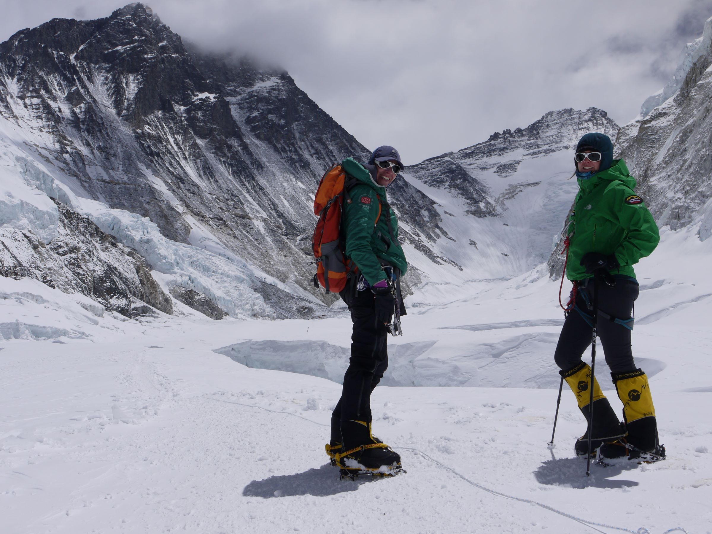 Two climbers stand in the Western Cwm looking towards the formidable Lhotse Face and Mount Lhotse.