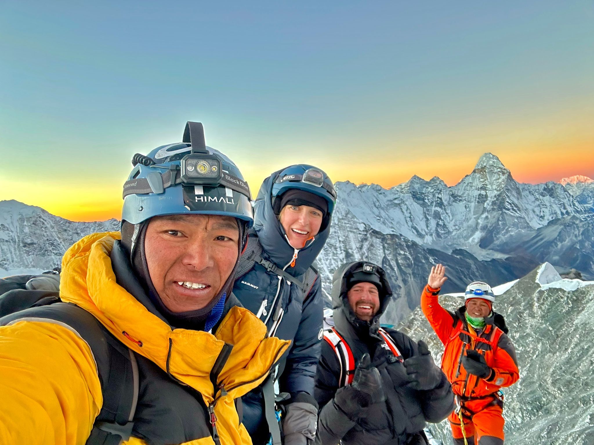 A team tops out on the summit of Island Peak with spectacular early morning skies all around.