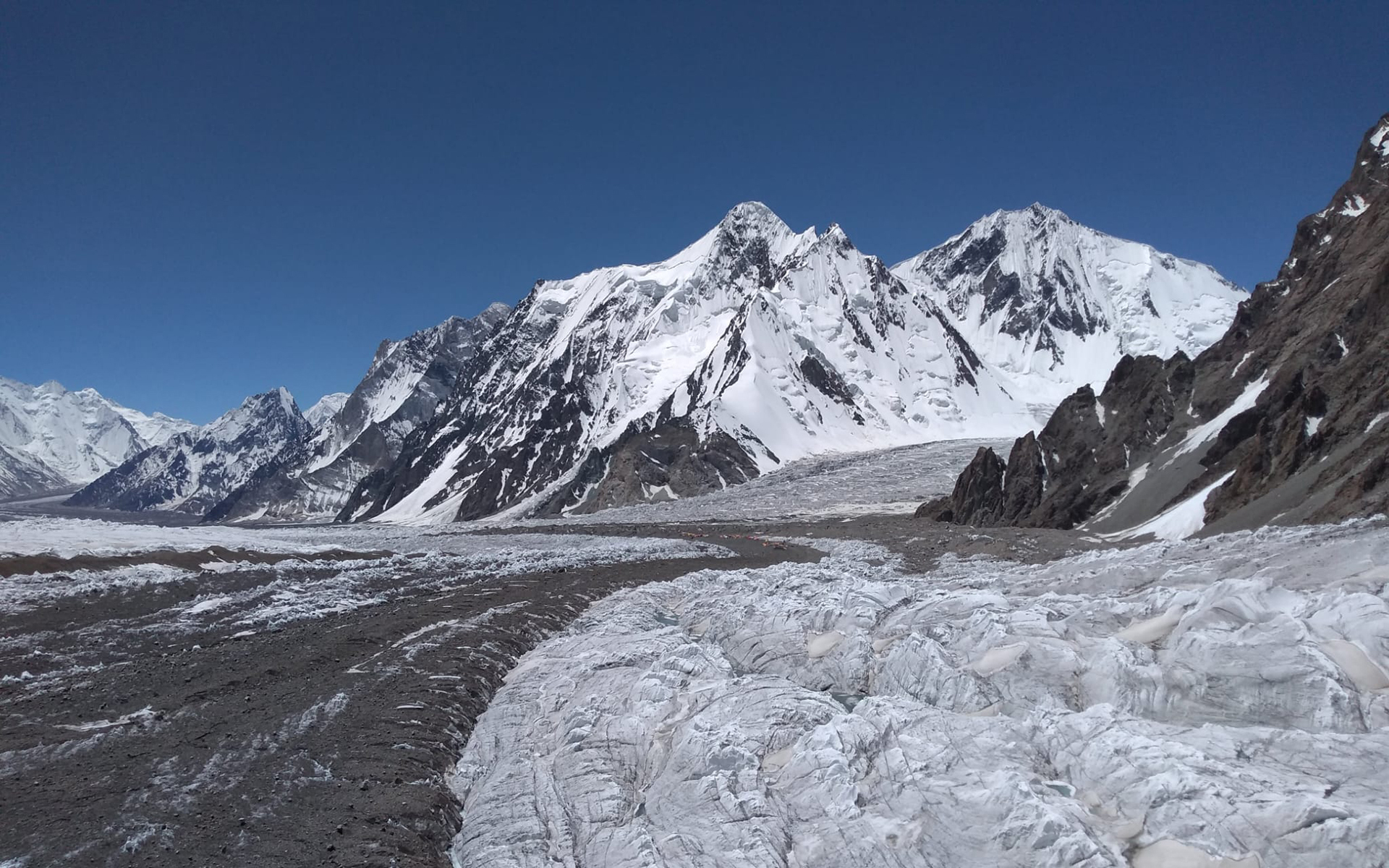 Tiny tents can be seen nestled along the huge glacier, sliding beneath the peaks of the Karakorum. Photo by AC Guide Rob Smith