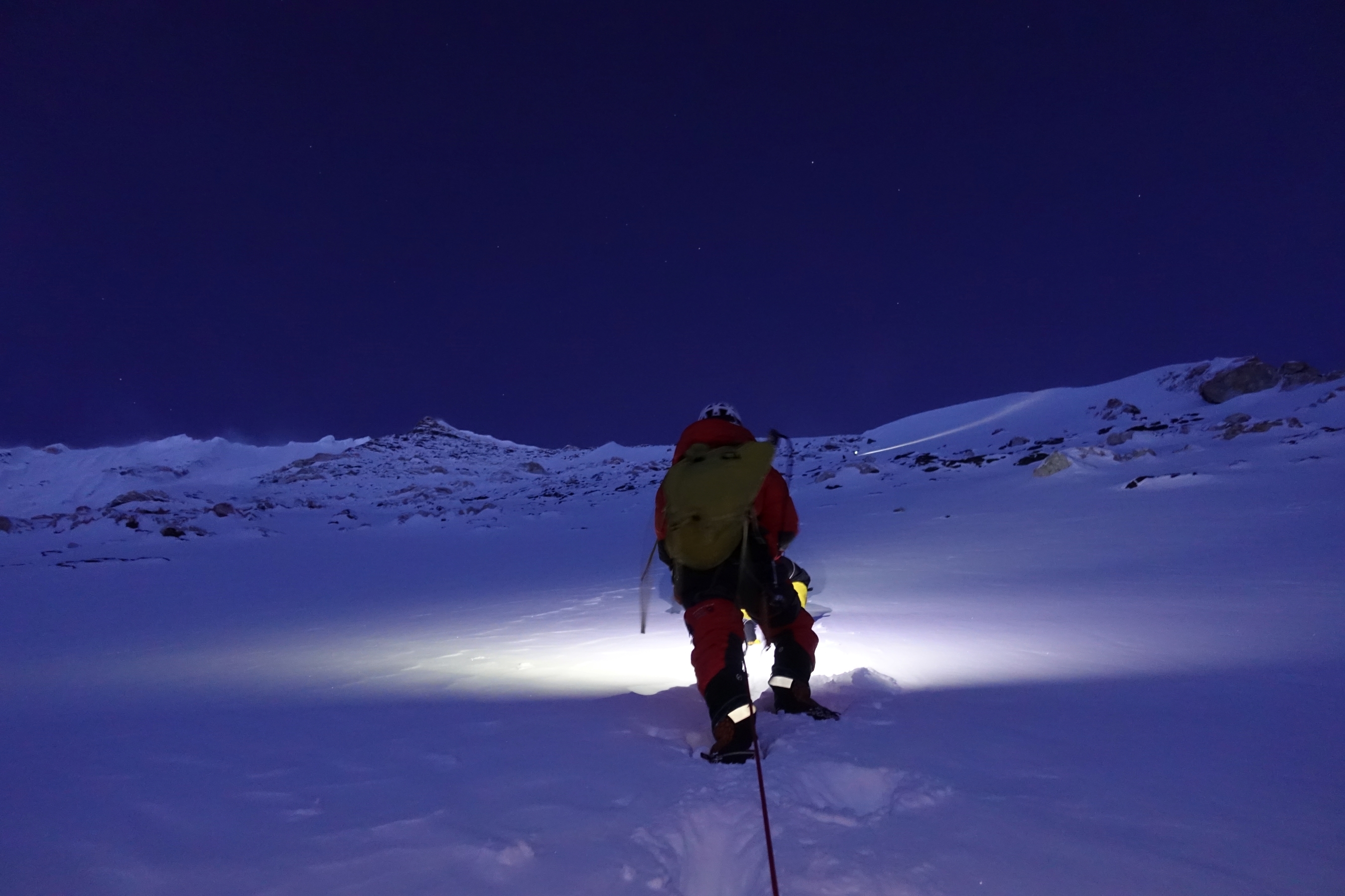 A climber in the pre-dawn dark climbs Nuptse with their headtorch