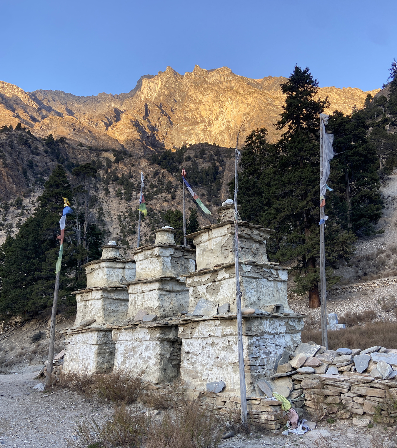 Trekking into Putha Hiunchuli base camp passes many Buddhist cultural and religious sites such as these chortens. Sun soaked peaks in the background.