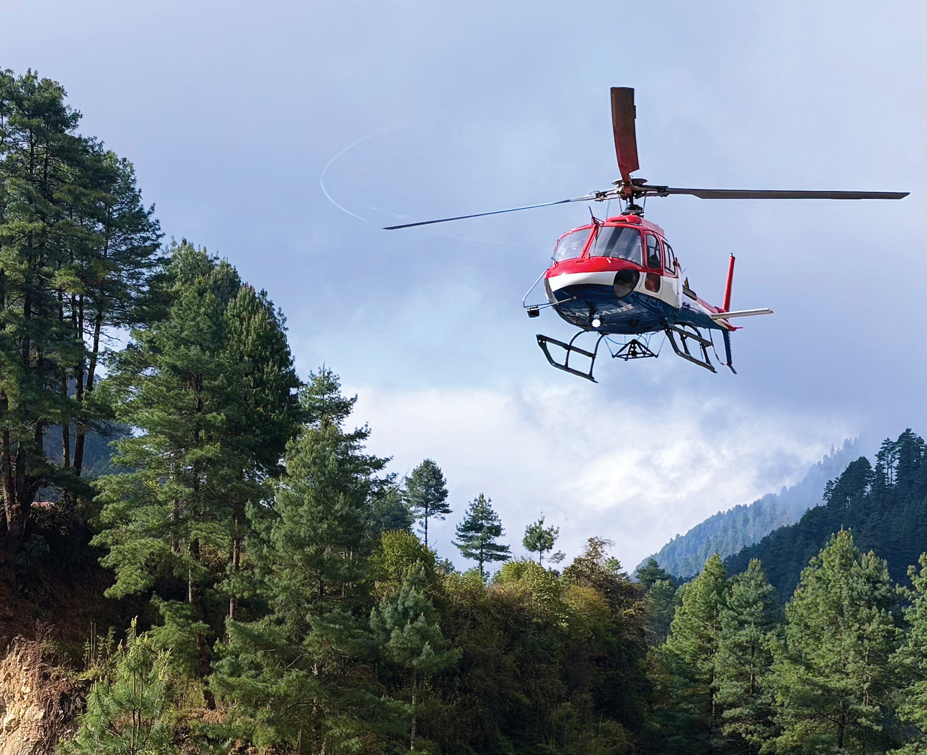 A helicopter comes in to land at lower altitudes near Monjo in the Khumbu Valley, Nepal. Photo by Tim Bouwkamp