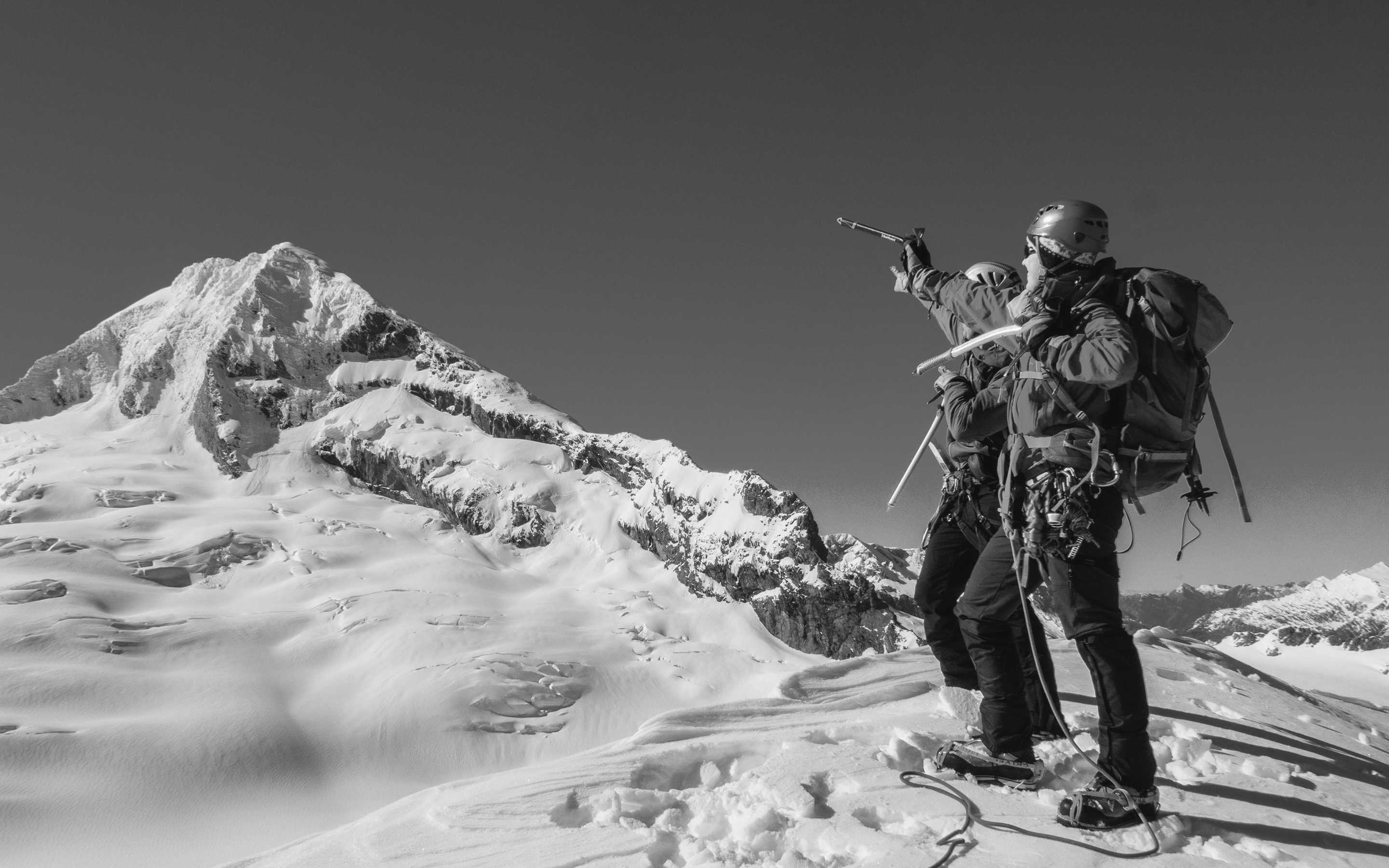Two climbers point towards a mountain in New Zealand's Southern Alps