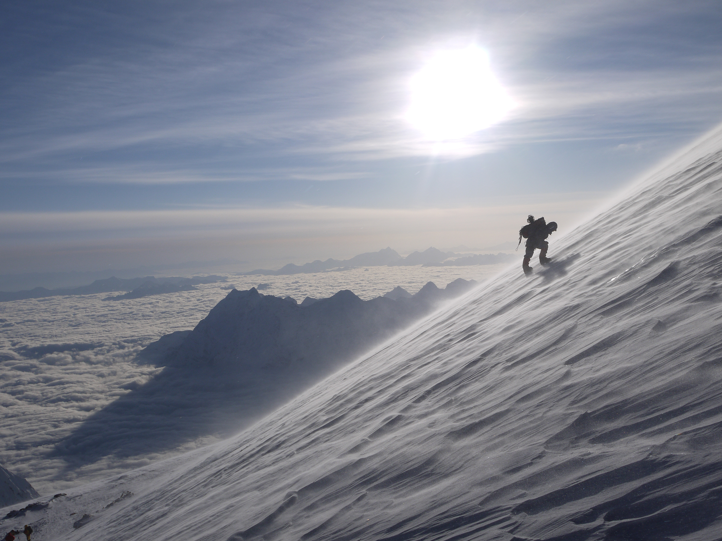 A climber bends over, resting on the steep upper slopes of Mount Manaslu, Nepal
