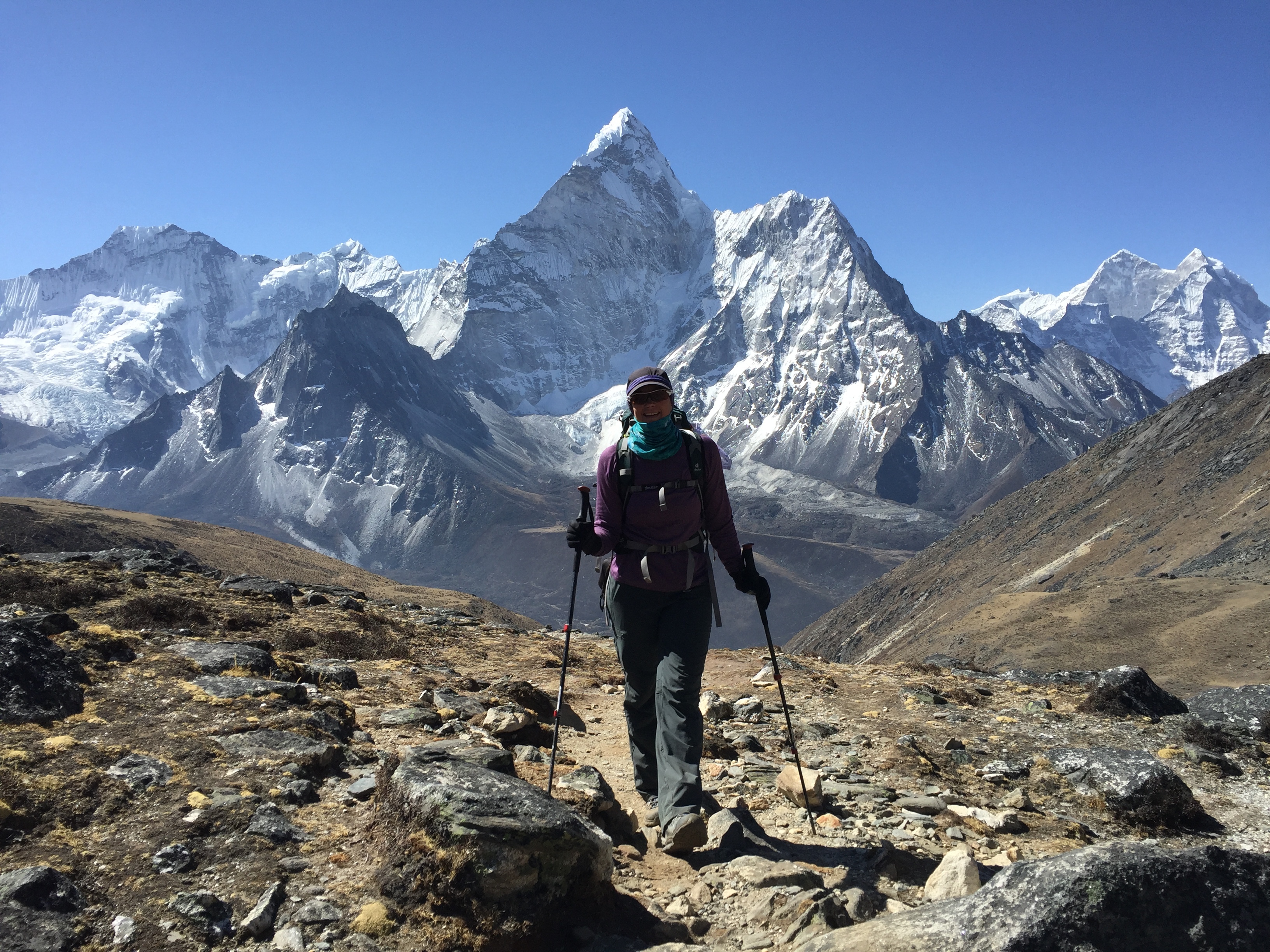 Trekker hikes high in Nepal’s Khumbu Valley, moving through rugged alpine terrain with towering Himalayan peaks ahead. Photo by Suze Kelly.