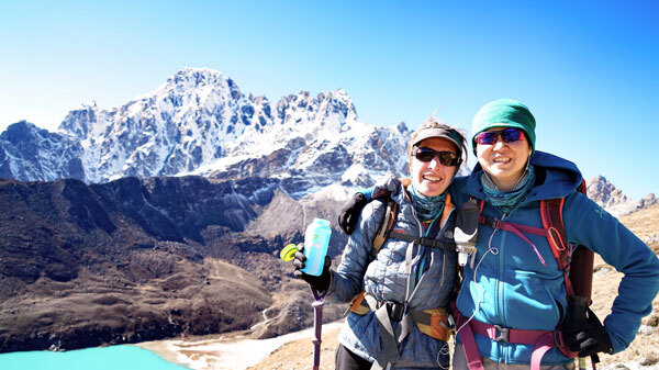 Staying hydrated on a remote Nepal trek, with glacial lakes and jagged Himalayan peaks framing the trail. Photo: Caroline Ogle