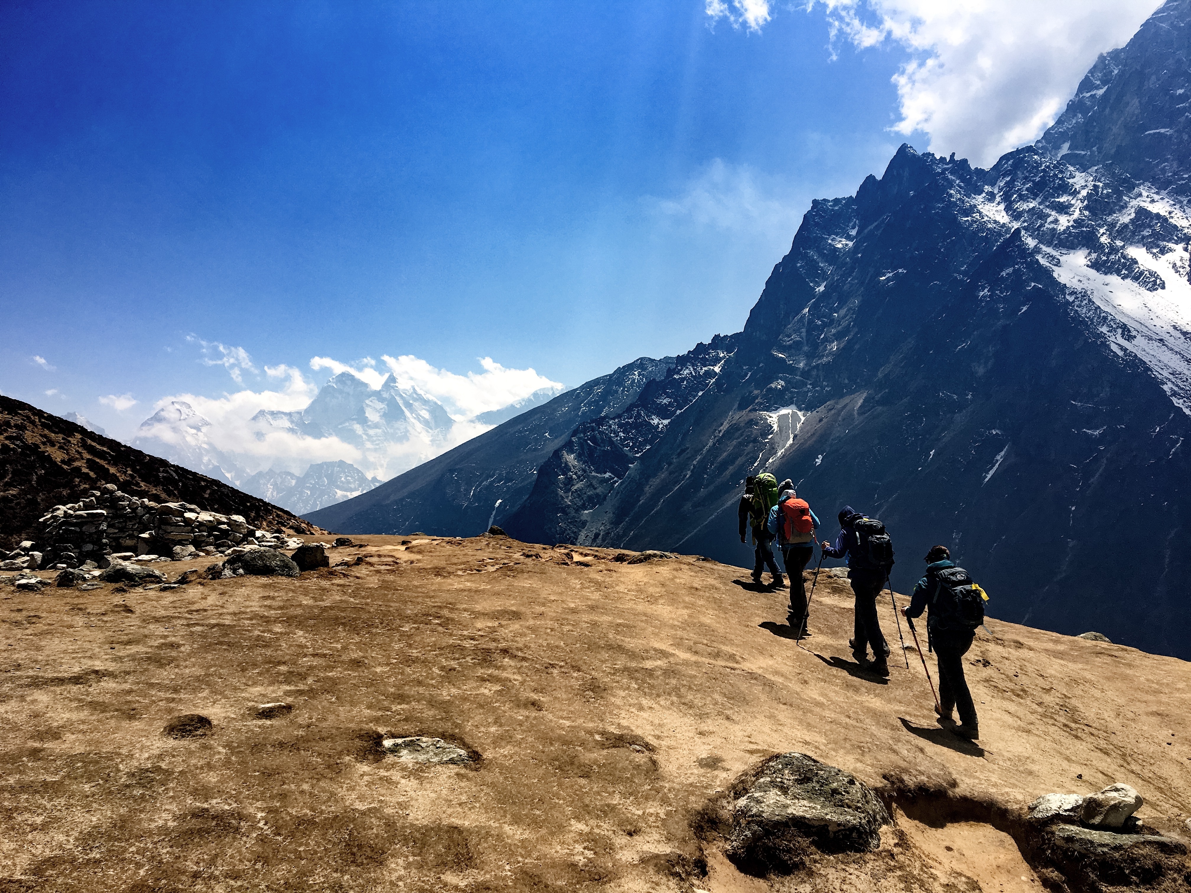 A trekking group heads down toward Dingboche, Nepal, crossing open alpine terrain beneath dramatic Himalayan ridgelines. Photo: Caroline Ogle