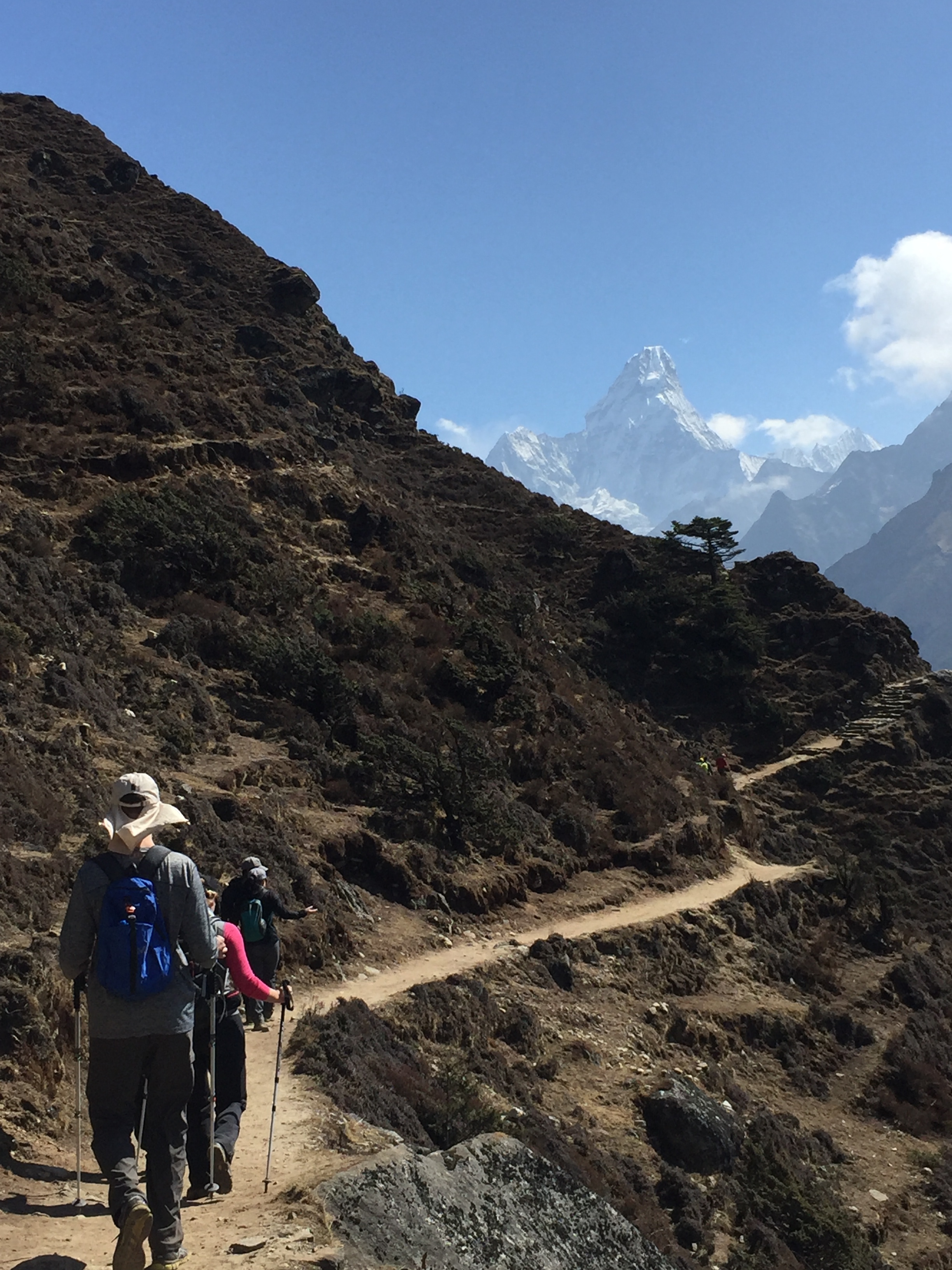 Hikers make their way along a high Khumbu Valley path, Ama Dablam rising sharply above the dry Himalayan slopes. Photo: Suze Kelly