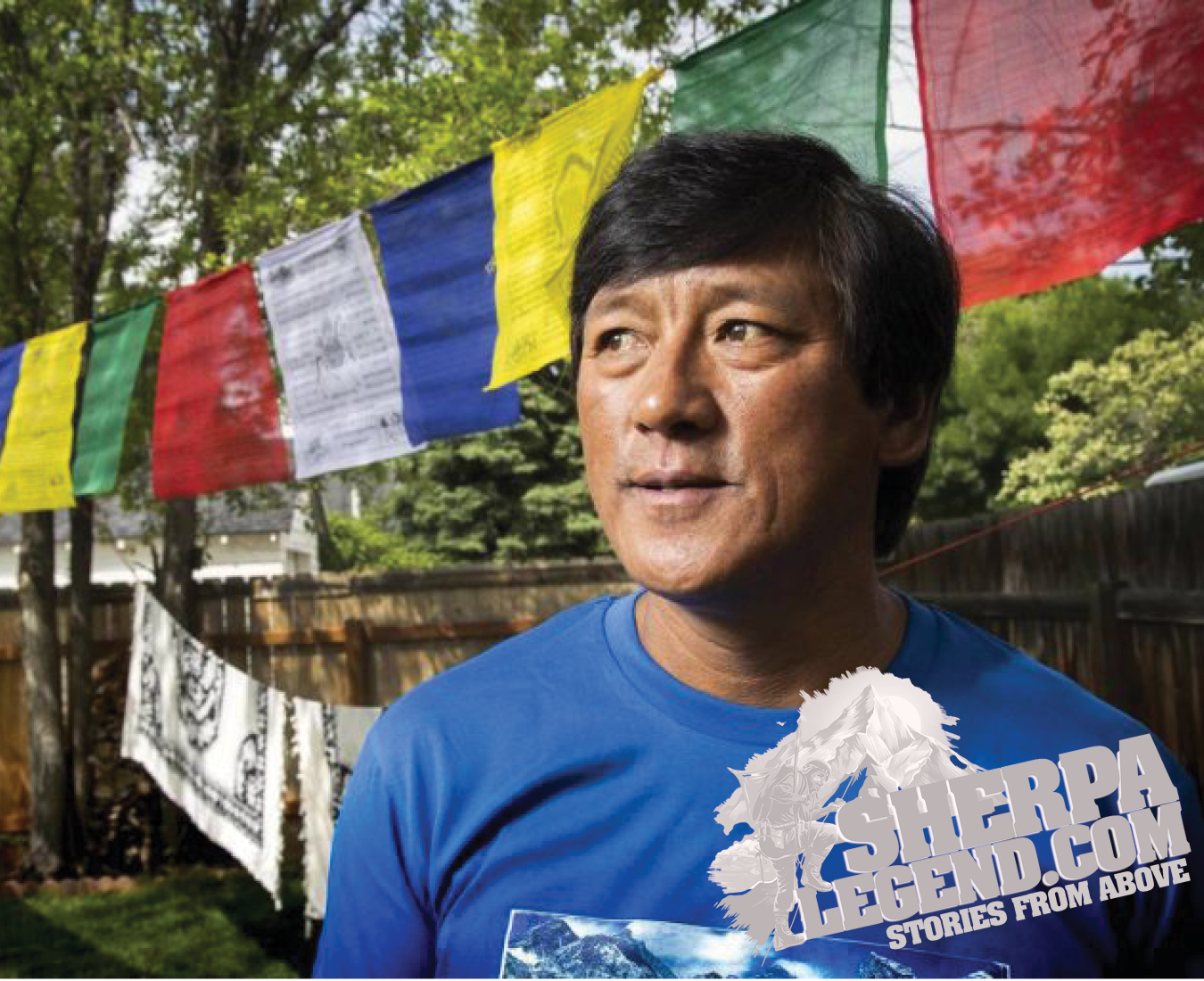 Ang Dorjee Sherpa poses at his home in the US, with prayer flags draped between trees in his yard.