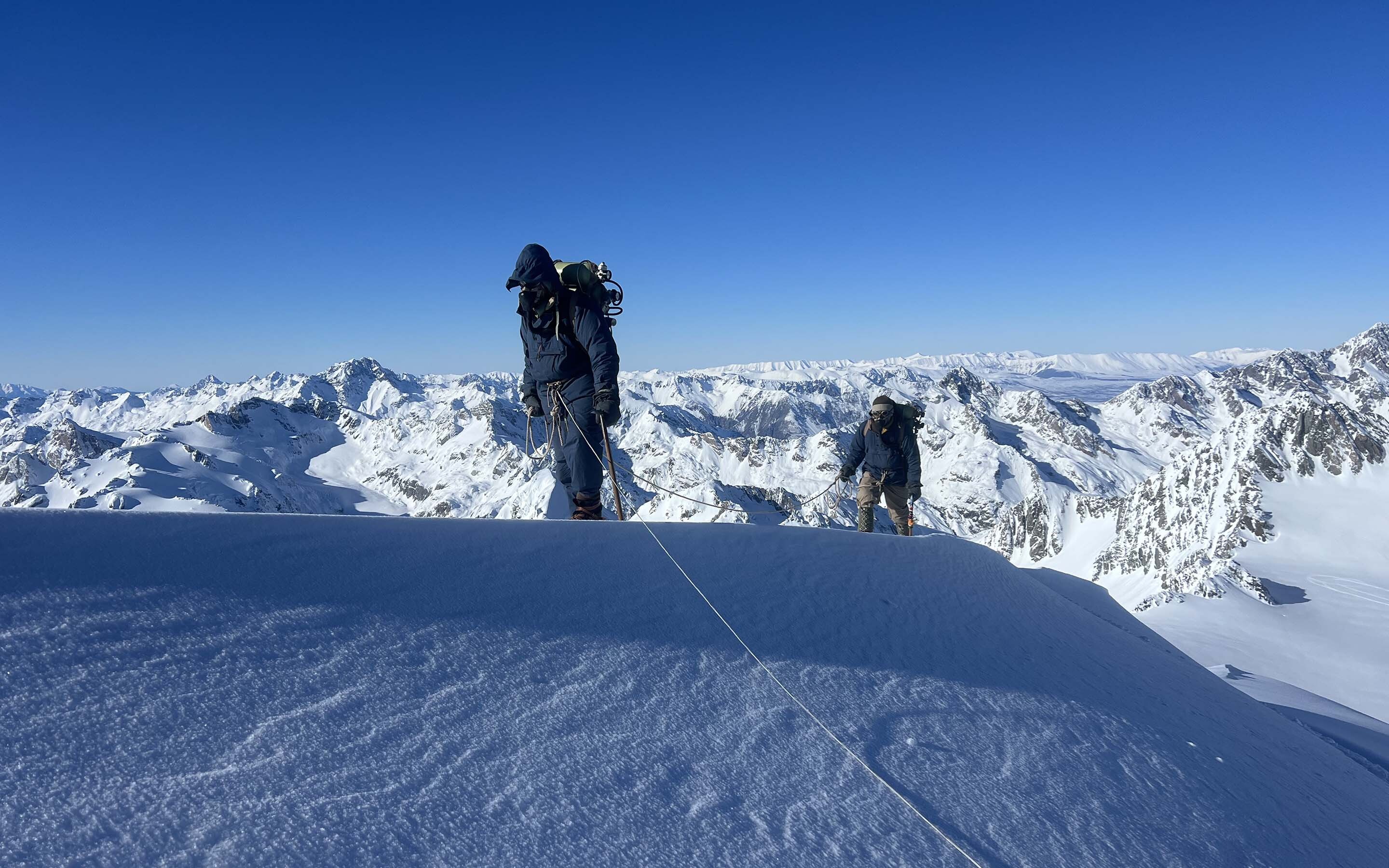 Two actors on the set of the Tenzing movie ascend a ridge line wearing clothing from the 1950s