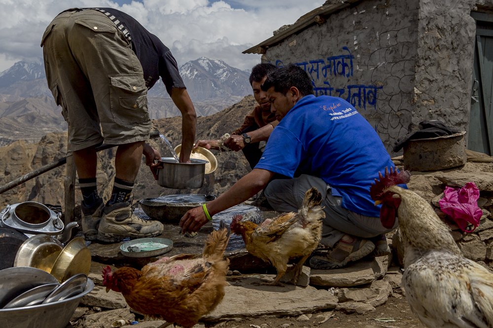 The AC Sherpa team washing dishes from a pipe being fed from a nearby stream in Upper Mustang.