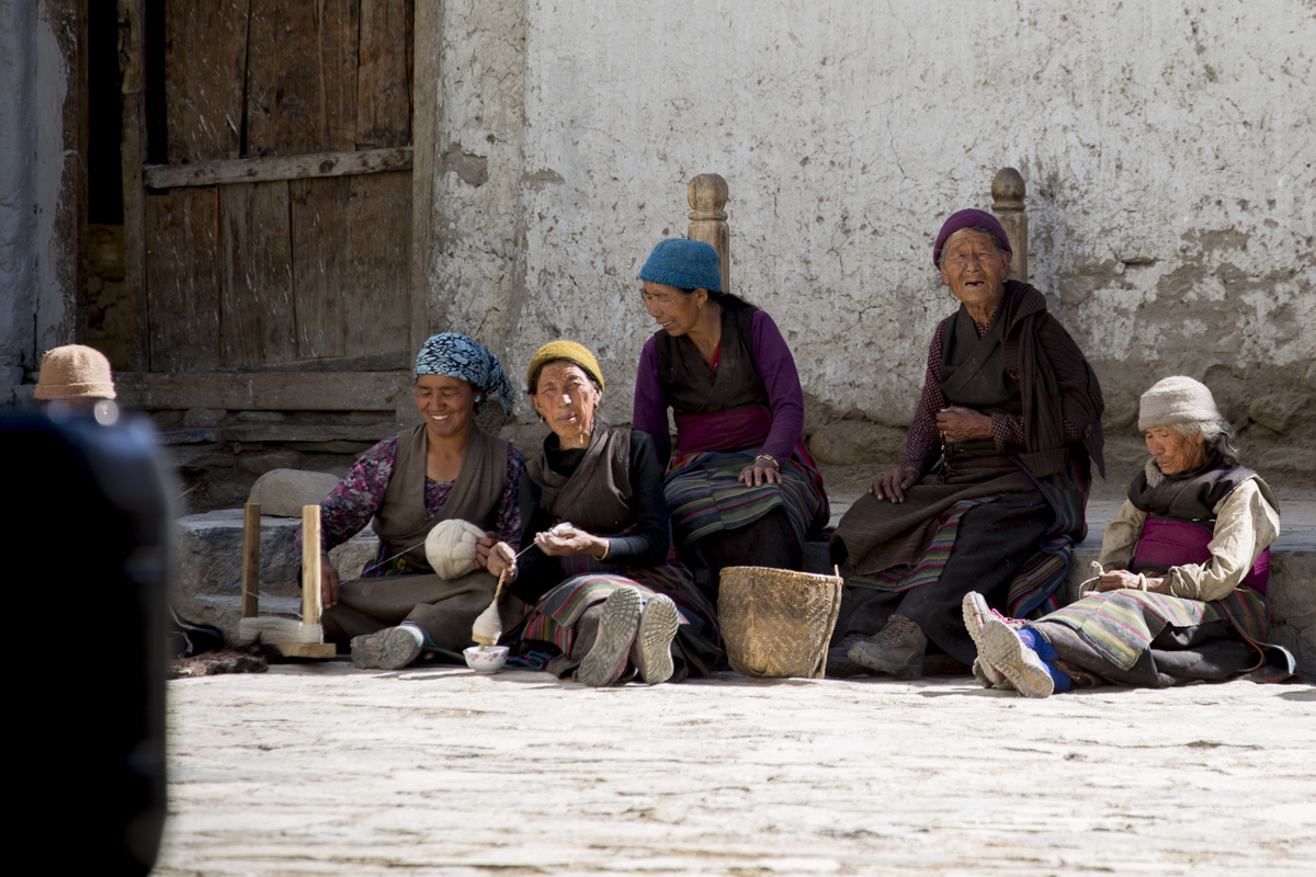 Local women line the streets in Lo Monthang, hand spinning yak wool used to make skirts and scarves.