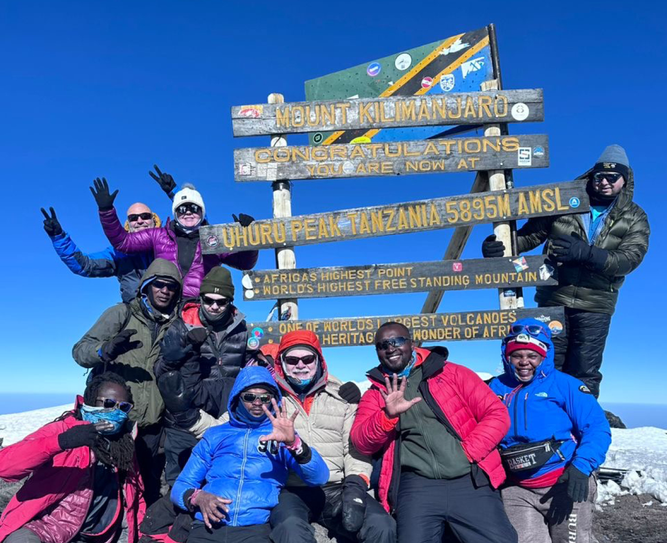 The AC Kilimanjaro Team #1 2025 celebrating on the summit of Uhuru Peak, Mount Kilimanjaro in cool but brilliantly clear conditions.