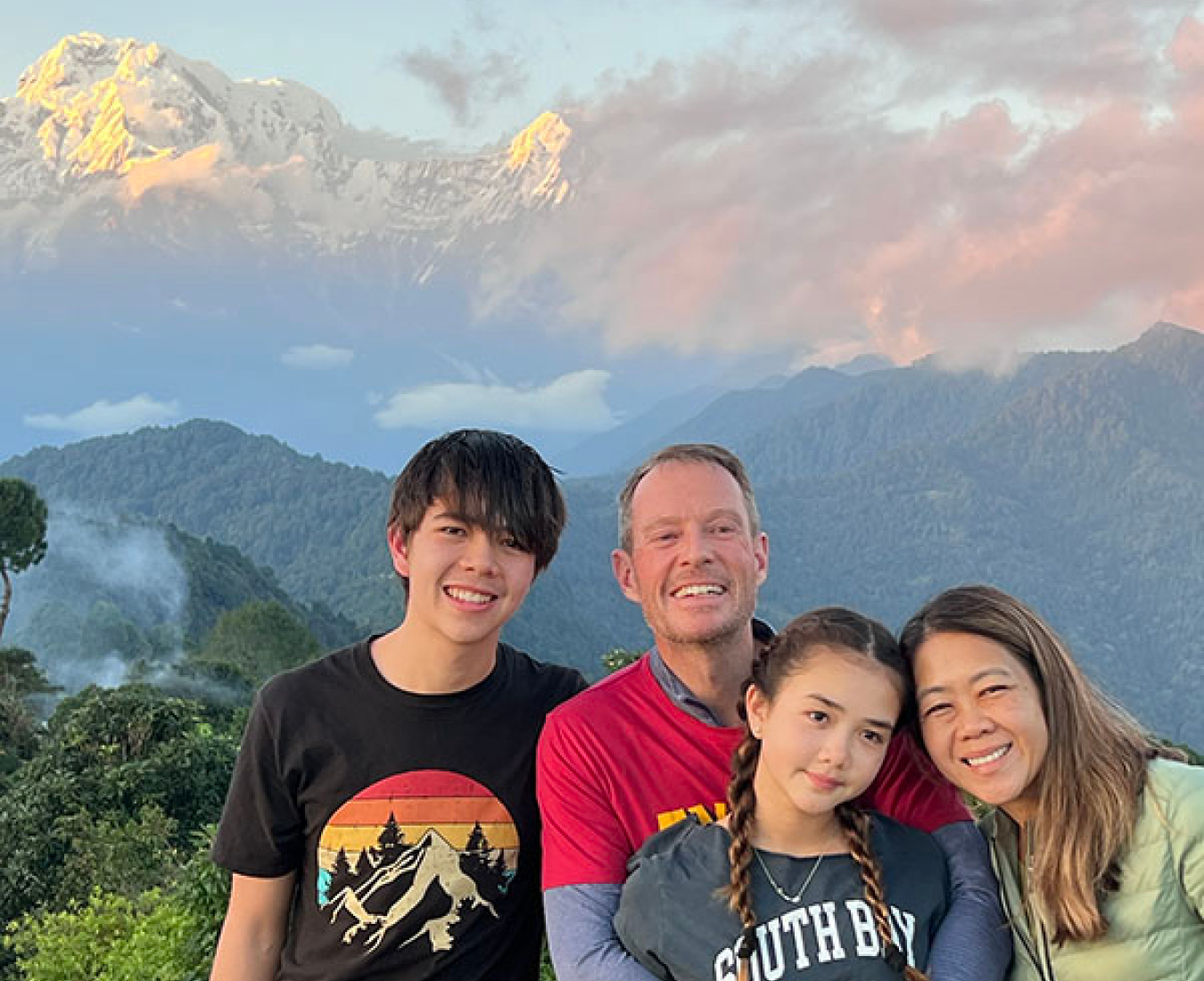 A family poses at sunset with the Annapurna rang behind while enjoying a custom private trek with Adventure Consultants.