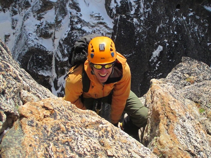 A climber smiles as he leads a climb on pitch 3 of the Beckey Route on Liberty Bell a granite spire in Washington Pass. Photo by Jason Martin, AAI