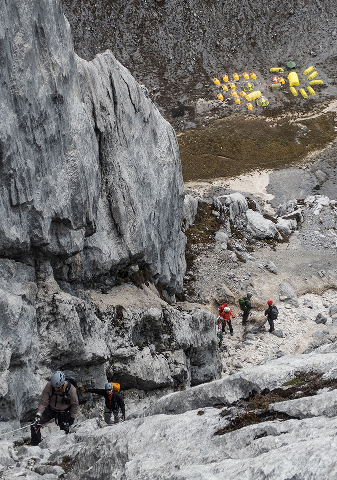 Climbers make their way up the lower reaches of Carstensz Pyramid with the yellow tents of base camp below.