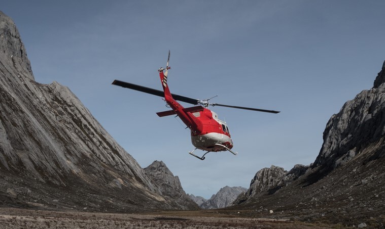 A helicopter takes off from Carstensz Pyramid Base Camp