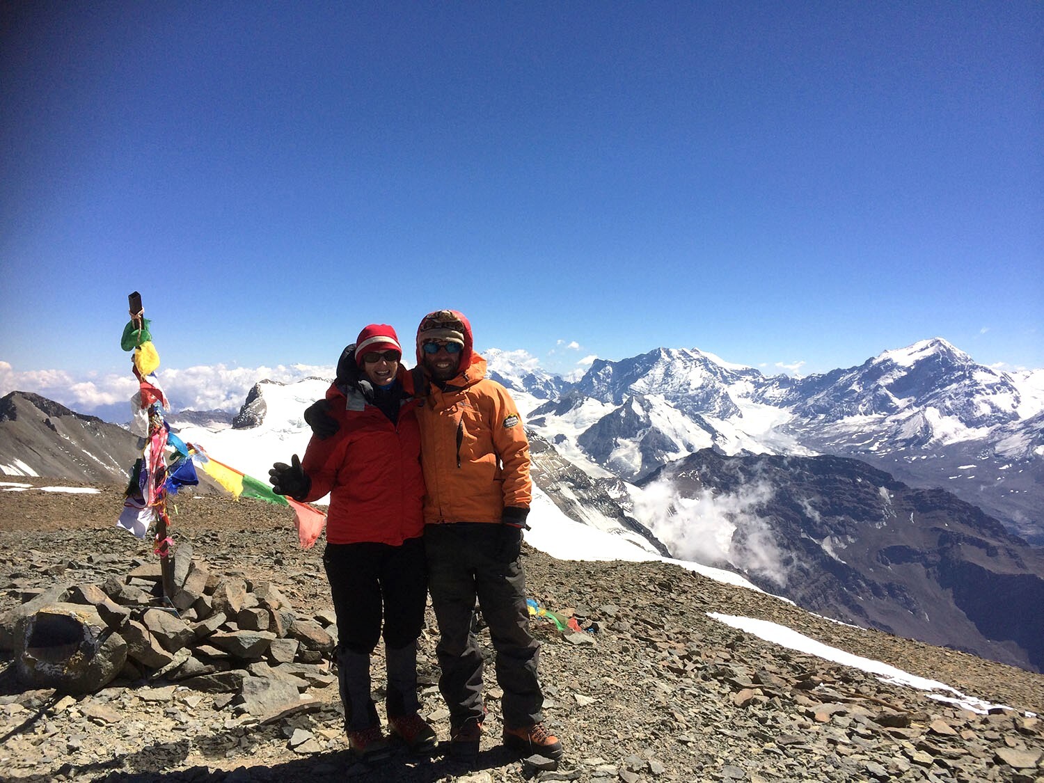 The expanse of the Andes behind two climbers standing on the summit of Cerro el Plomo