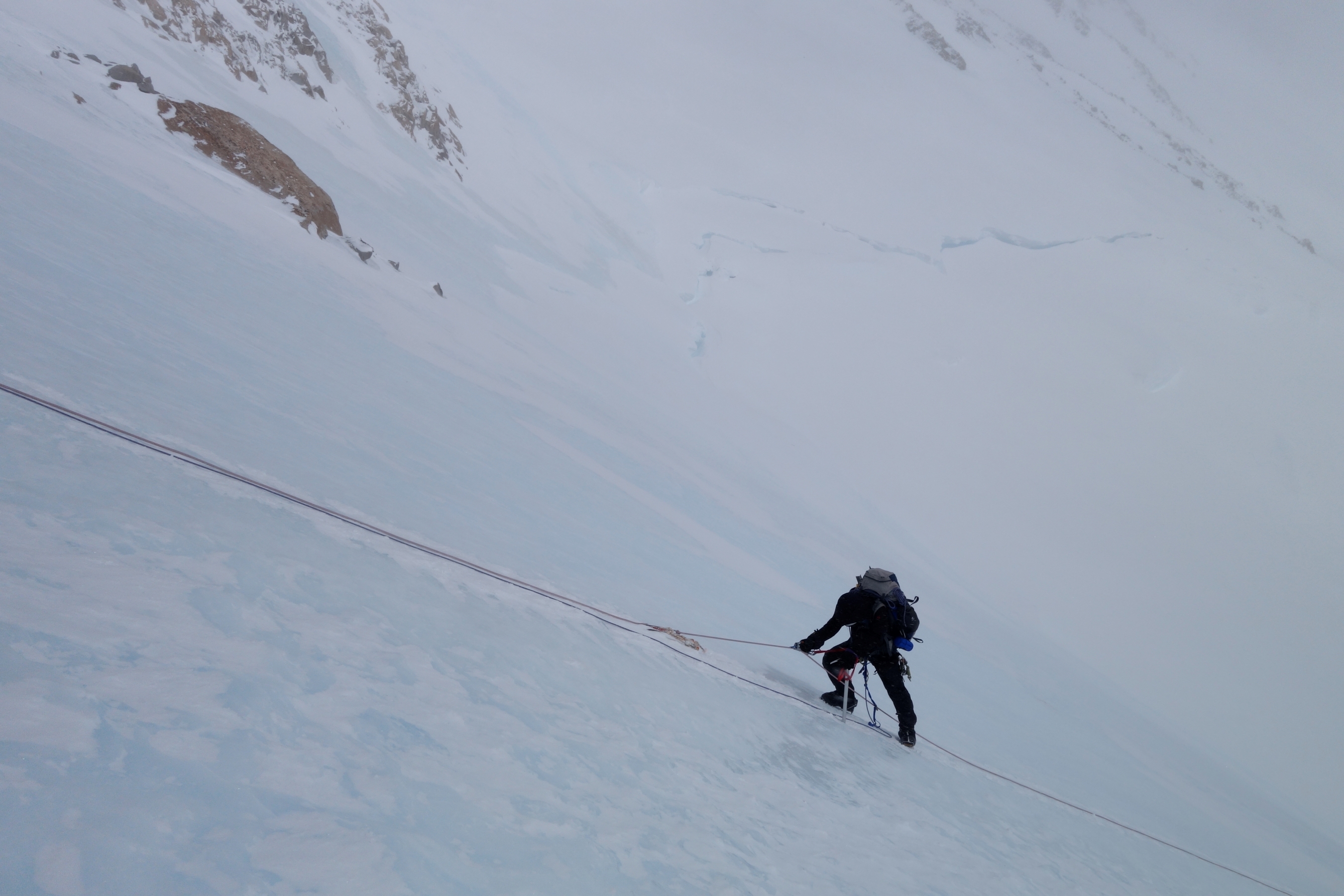 A climber ascends a steep fixed line on Denali.