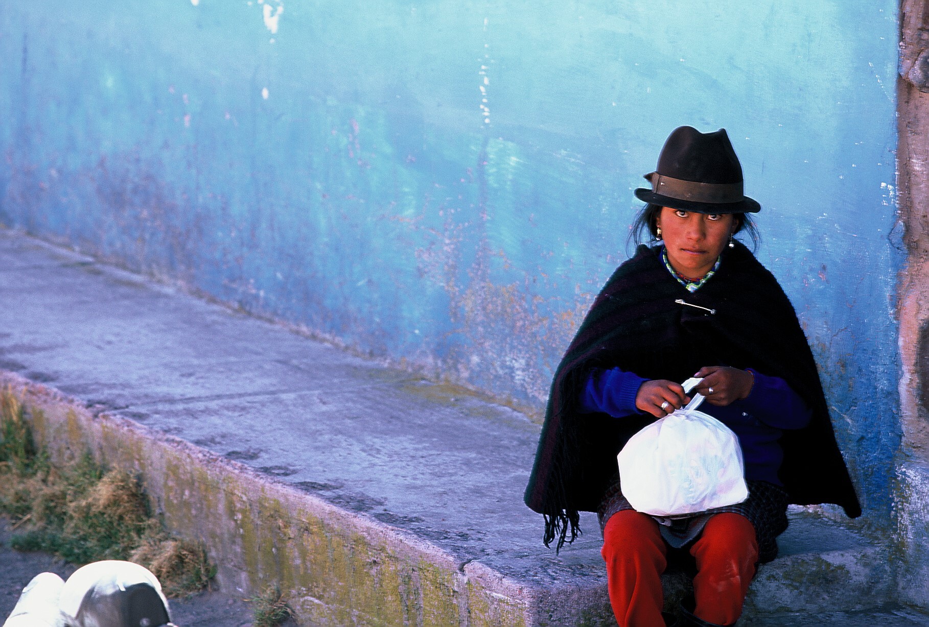 An Ecuadorian child sits on a concrete step in Quito