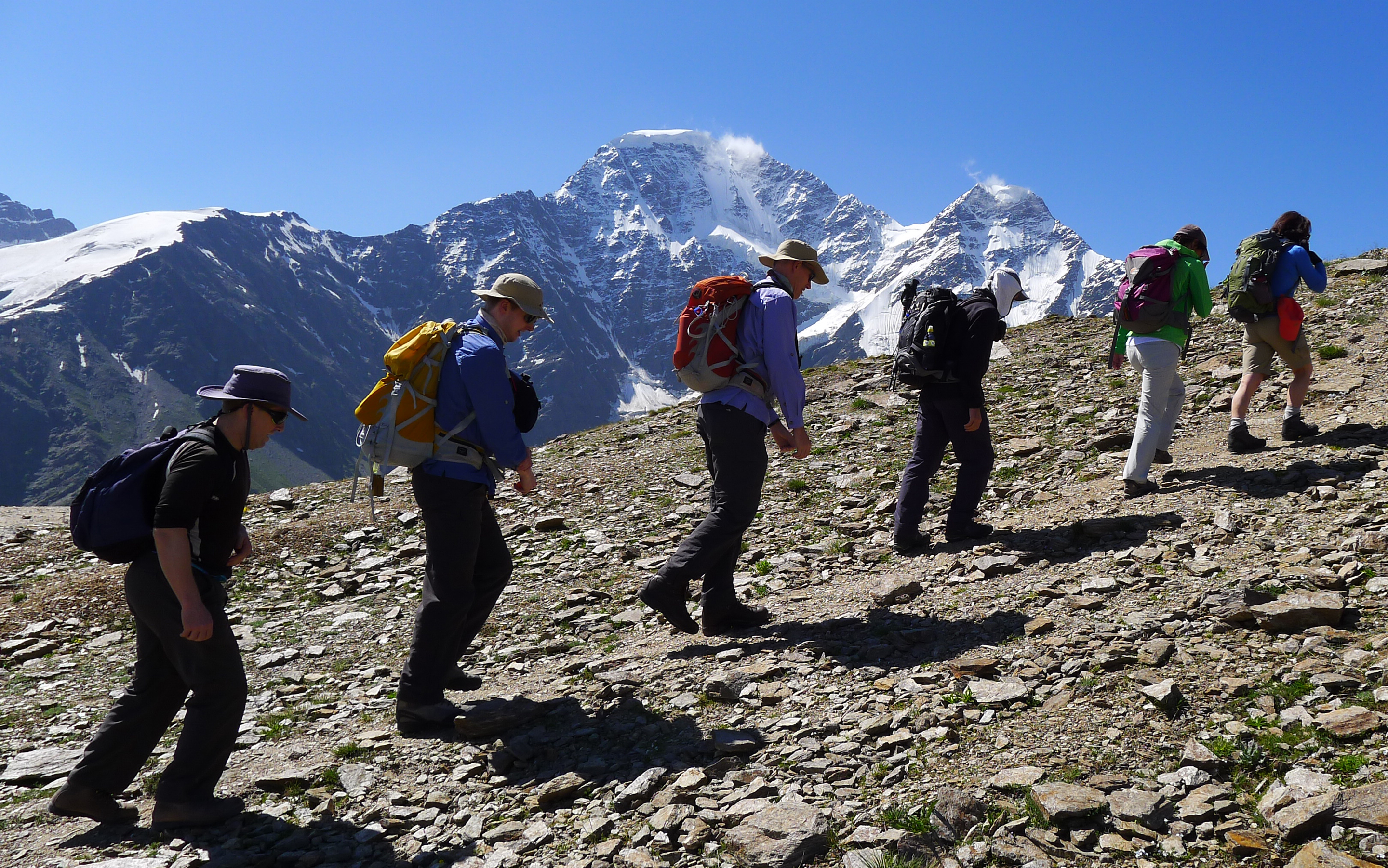 A team acclimatising with a day walk in the mountains around Elbrus, stunning snow capped peaks in the distance.