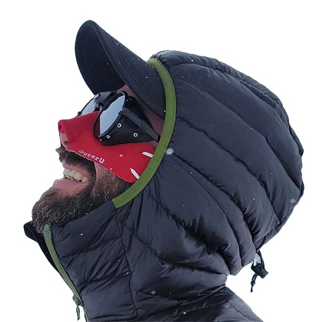 A climber wearing a bright red faceGlove FLEX, sunglasses and hooded down jacket.