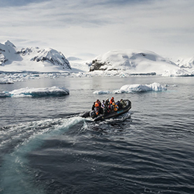 A zodiac heads to shore weaving between icebergs on the Antarctic Peninsula.